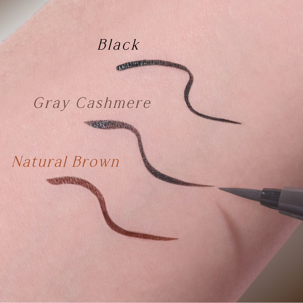 Three eyebrow pencil strokes on a pink background labeled 'Black', 'Gray Cashmere', and 'Natural Brown'.
