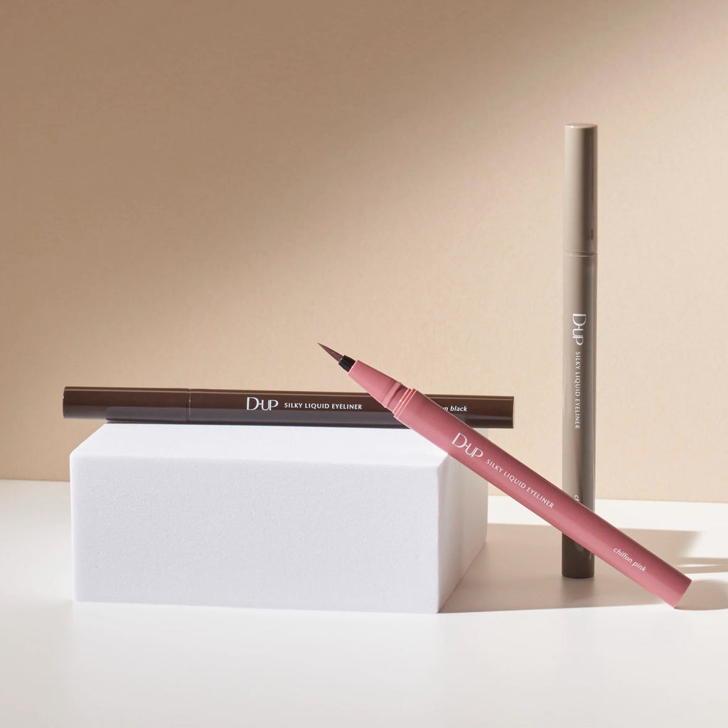 Two eyeliner pencils with visible branding on a beige background